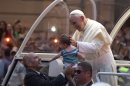 A member of the security detail holds up a baby to Pope Francis as he makes his way in the popemobile into central Rio de Janeiro, Brazil, Monday, July 22, 2013. The pontiff arrived for a seven-day visit in Brazil, the world's most populous Roman Catholic nation. During his visit, Francis will meet with legions of young Roman Catholics converging on Rio for the church's World Youth Day festival. (AP Photo/Felipe Dana)