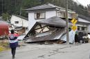 A man takes a photo of a damaged houses Sunday, Nov. 23, 2014 after a strong earthquake hit Hakuba, Nagano prefecture, central Japan, Saturday night. More than 20 people have been hurt after the magnitude-6.8 earthquake shook the mountainous area that hosted the 1998 winter Olympics. (AP Photo/Kyodo News) JAPAN OUT, CREDIT MANDATORY
