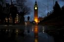 The Houses of Parliament are reflected in a puddle as they are illuminated in London, Britain