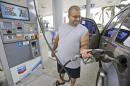 In this Wednesday, June 4, 2014 photo, Baltazar Rosado, of Hollywood, Fla., pumps gasoline into his car at a Chevron gasoline station in Pembroke Pines, Fla. The Labor Department reports on U.S. consumer prices in June on Tuesday, July 22, 2014. (AP Photo/Wilfredo Lee)