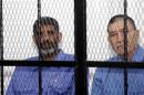 Abdullah al-Senussi and Bouzaid Dorda sit behind bars during a hearing at a courtroom in Tripoli