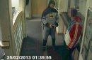 A man dressed as Batman and a burglary suspect stand in a police station in Bradford, northern England