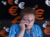 A woman speaks on her mobile phone as she stands next to euro signs in Madrid