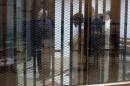 Muslim Brotherhood's Supreme Guide Mohamed Badie prays behind bars with other Muslim Brotherhood members at a court in the outskirts of Cairo