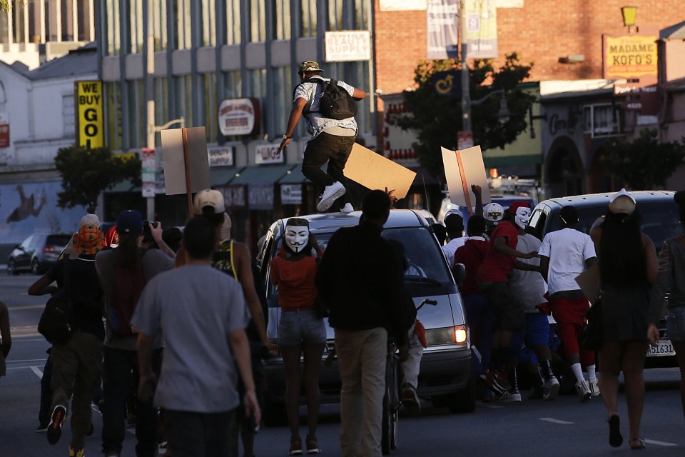 A protester stomps on a van during a demonstration in reaction to the acquittal of neighborhood watch volunteer George Zimmerman on Monday, July 15, 2013, in Los Angeles. Anger over the acquittal of a U.S. neighborhood watch volunteer who shot dead an unarmed black teenager continued Monday, with civil rights leaders saying mostly peaceful protests will continue this weekend with vigils in dozens of cities. (AP Photo/Jae C. Hong)