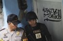 An official from the Special Detachment 88 squad and a police officer stand guard outside the house of a suspected militant after a raid in Jakarta
