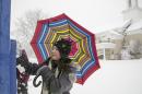 Hana Quinn, 10, wipes snow off the sign for the First Christian Church on South Calhoun Street as she holds her umbrella against the falling snow, Fort Wayne, Ind., Wednesday, March 12, 2014. (AP Photo/The Journal Gazette, Chad Ryan)