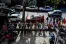 People queue to buy basic food and household items outside a supermarket in Caracas, on August 4, 2016