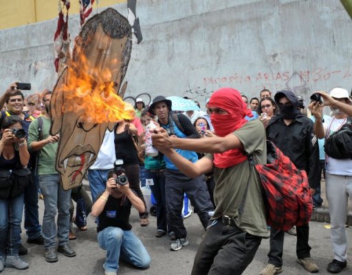 A protester burns a cardboard face of US President Barack Obama during a May Day rally in San Jose on May 1, 2013