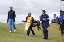 United States' Brooks Koepka, left, his caddie Ricky Elliott, center, and an official walk off the 11tth green after play was suspended due to high wind during the second round of the British Open Golf Championship at the Old Course, St. Andrews, Scotland, Saturday, July 18, 2015. (AP Photo/Alastair Grant)