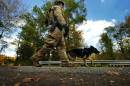 A member of law enforcement walks a K-9 dog to the woods Wednesday, Oct. 8, 2014, in Price Township near Canadensis, Pa., searching for killer Eric Frein. A massive manhunt has been underway for 31-year-old Frein in the rugged terrain of the Pocono Mountains since Sept. 12. The self-taught survivalist is charged with killing Cpl. Bryon Dickson and seriously wounding Trooper Alex Douglass outside their barracks in Blooming Grove. (AP Photo/Scranton Times & Tribune, Butch Comegys) WILKES BARRE TIMES-LEADER OUT; MANDATORY CREDIT