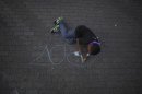 In this photo taken Tuesday, May 22, 2012, a boy colors in the letter "P" with chalk after spelling the Spanish word "Paz," or "Peace," at an event against violence, in Caracas, Venezuela. The government says more than 14,000 people were killed in Venezuela last year, giving the country a murder rate of 50 per 100,000 people and making it one of the most violent countries in Latin America and the world. The murder rate has more than doubled since 1998, when Venezuela's President Hugo Chavez was first elected. (AP Photo/Fernando Llano)