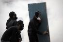 Bahraini protesters take cover behind a door during clashes with police after demonstration against the arrest of Sheikh Ali Salman, head of the Shiite opposition movement al-Wefaq, in Bilad al-Qadeem, on January 16, 2015