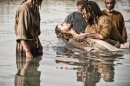 This publicity image released by History shows Diogo Morcaldo as Jesus, center, being baptized by Daniel Percival, as John, in a scene from "The Bible." The History network's first installment of the miniseries "The Bible" was seen by 13.1 million people Sunday, March 3. The series, produced by the husband-and-wife team of Mark Burnett and Roma Downey, will air in four more installments concluding March 31, Easter Sunday. (AP Photo/History, Joe Alblas)