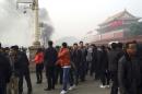 File photo of people walking along the sidewalk of Chang'an Avenue as smoke rises in front of the main entrance of the Forbidden City at Tiananmen Square in Beijing