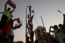 Iraqi youth climb on a pole with national flags during a demonstration to express support for Prime Minister Haider al-Abadi's reform drive on August 14, 2015 in Baghdad's Tahrir Square