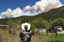 Tracy Bennett, ranch manager of Hidden Valley Ranch, a corporate retreat and guest ranch near Pecos, N.M., watches a large plume of smoke rise from a wildfire Friday, May 31, 2013. Bennett had to evacuate four guests the day before when the fast-moving fire in New Mexico's Santa Fe National Forest threatened the ranch and nearby cabins and vacation homes. (AP Photo/Barry Massey)