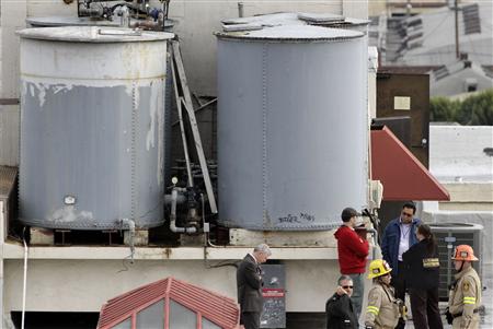 Authorities stand on the rooftop of the Cecil Hotel after a body was found in a water tank in Los Angeles, California, February 19, 2013. REUTERS/Jonathan Alcorn