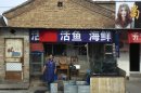 A vendor stands outside her store as the Chinese character for poultry is seen covered with a red cloth after it was prohibited from being sold in Naidong village, where a boy tested positive for the H7N9 virus, in Beijing Monday, April 15, 2013. The new case of bird flu in China's capital, a 4-year-old boy who displayed no symptoms, is adding to the unknowns about the latest outbreak that has caused 63 confirmed cases and 14 deaths, health officials said Monday. (AP Photo) CHINA OUT