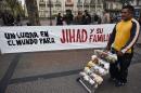 A street vendor passes a sign that reads in Spanish "A place in the world for Jihad and his family" placed by demonstrators in downtown Montevideo, Uruguay, Friday, Sept. 16, 2016. Former Guantanamo detainee Abu Wa'el Dhiab from Syria, also called Jihad, is on a hunger strike, threatening to die if he is not allowed to reunite with his family elsewhere, after he was resettled in Uruguay. (AP Photo/Matilde Campodonico)