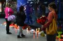 A woman carries flowers as people look at letters placed at Atocha railway station in Madrid on March 11, 2014 for the victims of the Madrid train bombings