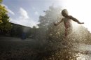 A girl cools off in the water from a playground sprinkler in the Brooklyn borough of New York