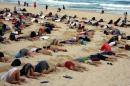 A group of around 400 demonstrators participate in a protest by burying their heads in the sand at Sydney's Bondi Beach