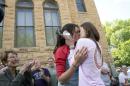 Jennifer Rambo, right, of Fort Smith, Ark., kisses her partner Kristin Seaton, left, of Jacksonville, Ark., following their marriage ceremony in front of the Carroll County Courthouse as Sheryl Maples, far left, the lead attorney who filed the Wright v. the State of Arkansas lawsuit, looks on Saturday, May 10, 2014, in Eureka Springs, Ark. Rambo and Seaton were the first same-sex couple to be granted a marriage license in Eureka Springs after a judge overturned Ammendment 83, which banned same-sex marriage in the state of Arkansas. (AP Photo/Sarah Bentham)