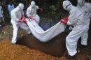 In this photo taken Saturday, Oct. 18, 2014, a burial team in protective gear buries a person suspected to have died of Ebola in Monrovia, Liberia. Even as Liberians get sick and die of Ebola, many beds in treatment centers are empty because of the government’s order that the bodies of all suspected Ebola victims be cremated. The edict violates Liberians’ values and cultural practices and has so disturbed people that the sick are often being kept at home and, if they die, are being secretly buried, increasing the risk of more infections. (AP Photo/Abbas Dulleh)