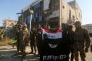 Iraqi security forces place the Iraqi flag above the Islamic State group flag on December 28, 2015 in front of the Anbar police headquarters after they recaptured Ramadi