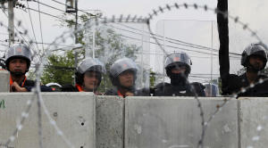 Thai riot police stand guard behind police barricades …