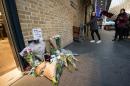 Floral tributes (L) to British actor Alan Rickman are seen as people pose at the Platform 9 3/4 Harry Potter display at King's Cross station in London, on January 15, 2016