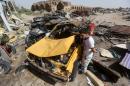 An Iraqi man stands next to the wreckage of cars in the aftermath of a massive suicide car bomb attack carried out by the Islamic State group in the predominantly Shiite town of Khan Bani Saad on July 18, 2015