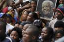 People hold a portrait of former South African President Mandela during his Memorial Service in Johannesburg