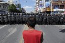 A protester stands in front of a lines of riot police officers Saturday July 28, 2012 in Qidong, Jiangsu Province, China. Authorities in eastern China dropped plans for a water-discharge project Saturday after thousands of protesters angry about pollution took to the streets, in the latest of many such confrontations in a country where three decades of rapid economic expansion have come at an environmental price. (AP Photo/Eugene Hoshiko)