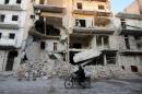 A man rides a motorcycle past damaged buildings in al-Myassar neighborhood of Aleppo, Syria