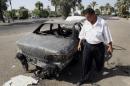 In this Sept. 25, 2007 file photo, an Iraqi traffic policeman inspects a car destroyed by a Blackwater security detail in al-Nisoor Square in Baghdad, Iraq. A federal jury reached a verdict Wednesday in the case of four former Blackwater security guards on trial in the shootings of more than 30 Iraqi citizens in the heart of Baghdad. The verdicts were to be read during a late-morning court session. The shootings triggered an international uproar over the role of defense contractors in urban warfare. (AP Photo/Khalid Mohammed, File)