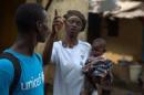 A UNICEF worker speaks with a woman, who is holding an infant, in the Matam neighborhood of Conakry