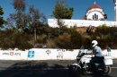 A policeman rides his motorcycle in front of Golden Dawn and nationalist graffiti in southern Greece, on September 29, 2013