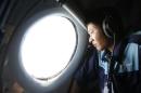 Military officer Nguyen Tran looks out from a Vietnam Air Force AN-26 aircraft during a mission to find the missing Malaysia Airlines flight MH370, off Con Dao island