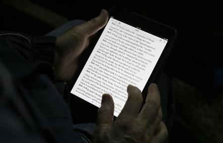 A man reads the bible from an iPad mini at the "Christ is the Answer International Ministries" group's camp near Florence February 2, 2013.