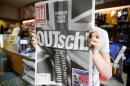 A man holds up the German newspaper Bild with the titel "OUTsch!", for the camera, in Berlin