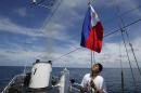 Philippine Navy crew member aboard a civilian supply ship raises a Philippine national flag after ship was able to evade an attempted blockade by Chinese vessels at disputed Second Thomas Shoal in South China Sea