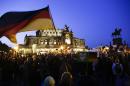 A protestor waves a German flag as he attends a demonstration of PEGIDA (Patriotic Europeans against the Islamization of the West) in front of the Semperoper, Dresden's famous opera house, in Dresden, Germany, Monday, Oct. 12, 2015. (AP Photo/Markus Schreiber)