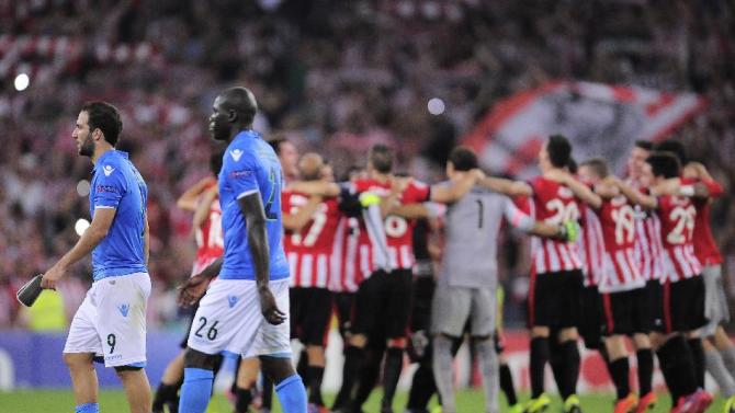 Athletic Bilbao&#39;s players celebrate after winning the match as SSC Napoli&#39;s Gonzalo Higuain of Argentina, left, and Kalidou Koulibaly of France, leave the pitch, during their Champions League playoff second leg soccer match, at San Mames stadium in Bilbao, northern Spain, Wednesday, Aug. 27, 2014.  Athletic Bilbao won 3-1