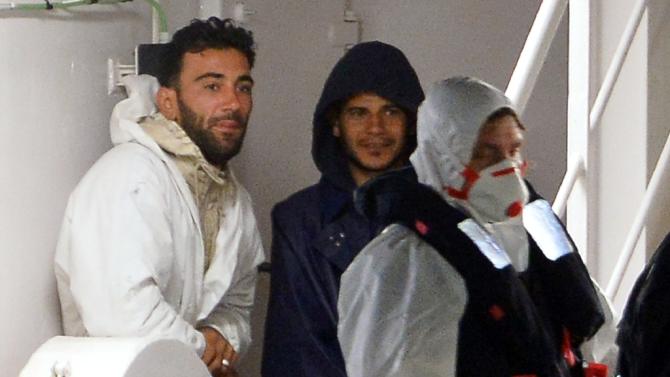 Mohammed Ali Malek (L), one of the survivors and captain of the boat that overturned off the coasts of Libya, and a man identified as Mahmud Bikhit (C), crew member of the boat, stand onboard the Italian Coast Guard vessel on April 20, 2015
