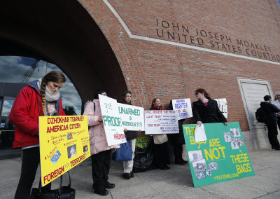 Protesters hold up signs outside federal court in Boston, Thursday, Dec. 18, 2014, where the final hearing for Boston Marathon bombing suspect Dzhokhar Tsarnaev was held before his trial begins in January. Tsarnaev is charged with carrying out the April 2013 attack that killed three people and injured more than 260. He could face the death penalty if convicted. (Elise Amendola/(AP Photo)