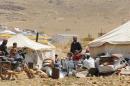 Refugees who fled the violence from the Syrian town of Flita, near Yabroud, stand outside their tents at the border town of Arsal