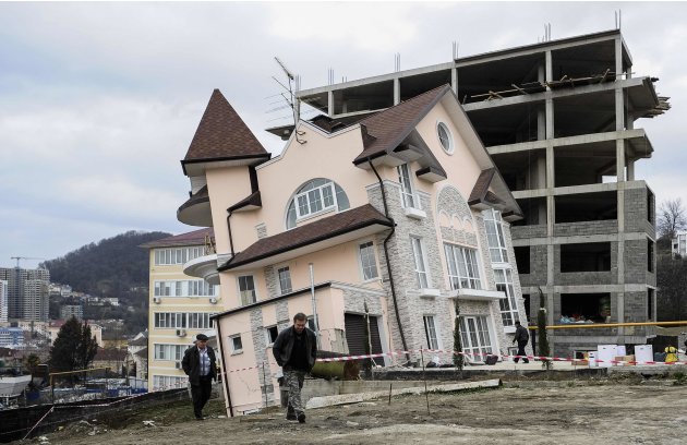 Men walk around a residential house that started leaning after a tunnel collapse in the Russian Black sea resort of Sochi