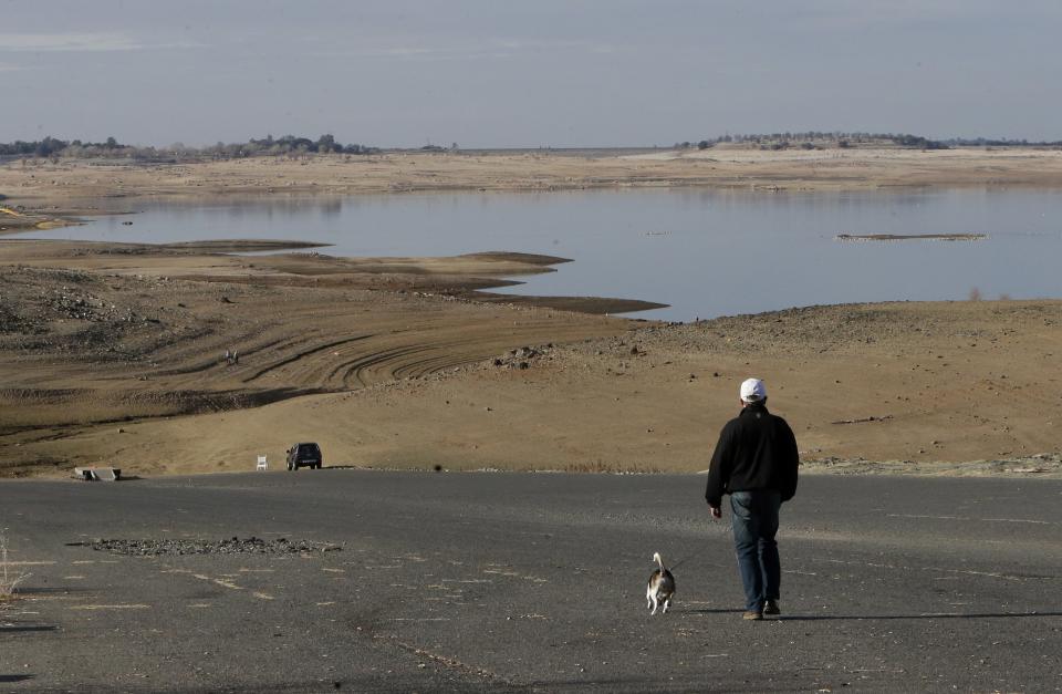 FILE - In this Jan. 9, 2014 file photo, a visitor to Folsom Lake, Calif., walks his dog down a boat ramp that is now several hundred yards away from the waters' edge. Gov. Jerry Brown formally proclaimed California in a drought Friday Jan. 17, 2014, saying the state is in the midst of perhaps its worst dry spell in a century and the conditions are putting residents and their property in "extreme peril." (AP Photo/Rich Pedroncelli, File)